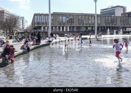 Bradford, West Yorkshire, Großbritannien, 6. April 2015. Erwachsene, Kleinkinder und Jugendliche genießen die Stadtpark mirror Pool und Brunnen im Centenary Square, Großbritanniens größte Stadtzentrum Wasserspiel. Niquab überdachte Frau am Telefon in der heißen Sonne. Bildnachweis: Mick Flynn/Alamy Live-Nachrichten Stockfoto