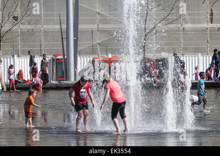 Bradford, West Yorkshire, Großbritannien, 6. April 2015. Erwachsene, Kleinkinder und Jugendliche genießen die Stadtpark mirror Pool und Brunnen im Centenary Square, Großbritanniens größte Stadtzentrum Wasserspiel. Eine glückliche multikulturelle Mischung von Menschen, Paddeln, Sonnenbaden und Spaß auf einer sonnigen Bank Ostern Montag. Bildnachweis: Mick Flynn/Alamy Live-Nachrichten Stockfoto