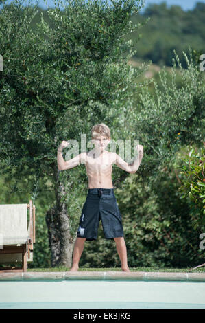 Ein kleiner Junge in schwarze Badehose Posen am Pool im Urlaub Stockfoto