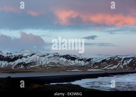 Der Sonnenuntergang über Vik schwarzen Sandstrand auf der South Island, mit den vulkanischen Klippen im Hintergrund Stockfoto