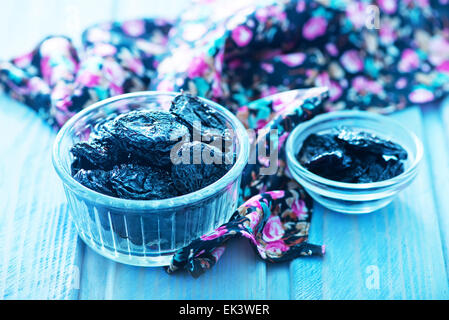 trockene Pflaumen in Schüssel geben und auf einem Tisch Stockfoto