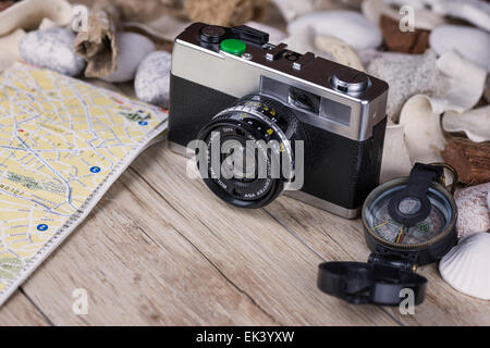 Im Bild eine analoge Kamera Film, einen Kompass und eine Karte, auf den Seiten Muscheln und dekorativen Steinen. Stockfoto