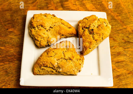 Frisch gebackenen Zimt und Rosinen Scones auf einer weißen quadratischen Platte Stockfoto