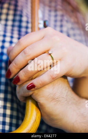 Ein Brautpaar Hände halten einen Regenschirm zusammen. Die Frau trägt einen Verlobungsring. Stockfoto