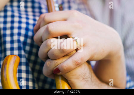 Ein Brautpaar Hände halten einen Regenschirm zusammen. Die Frau trägt einen Verlobungsring. Stockfoto