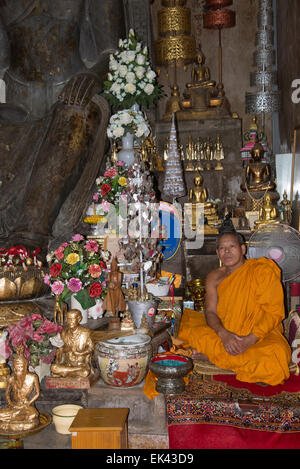 Buddhistischer Mönch sitzt im Wat Na Phra Mane Tempel von Ayutthaya Thailand trägt die traditionelle Orange gefärbte Gewand Stockfoto