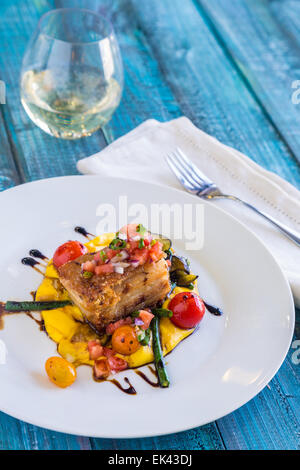 Knuspriger Schweinebauch auf Kabocha Squash-Püree mit Tomaten und Spargel, garniert mit Pico de gallo Stockfoto