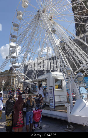 Bradford Eye, Big Wheel an einem sonnigen Tag. Familie warten auf den Riesen Bord anzeigen Rad, Rathaus im Blick. Stockfoto