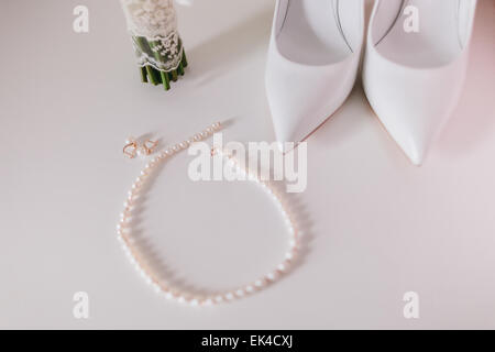 Hochzeit Perlen Ohrringe und Halskette hautnah mit Hochzeitsschuhe und Strauß-Hintergrund Stockfoto