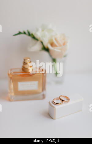 Trauringe Closeup mit Braut Parfum und Knopfloch Hintergrund Stockfoto