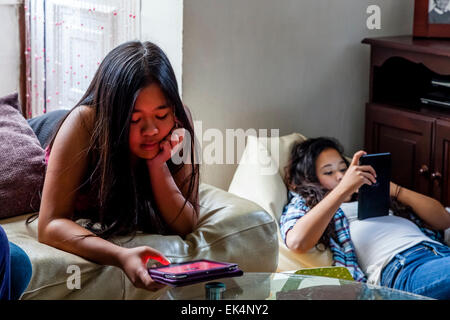 Zwei Mädchen spielen auf Ihren Ipads/Tabletten, Sussex, UK Stockfoto