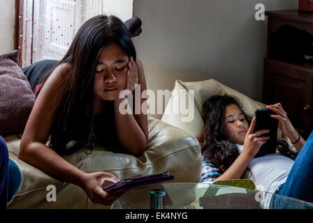 Zwei Mädchen spielen auf Ihren Ipads/Tabletten, Sussex, UK Stockfoto