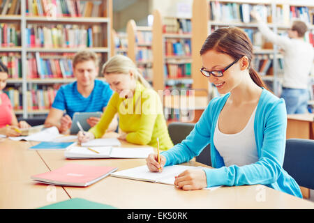Hübsche Studentin Notizen in der Universitätsbibliothek Stockfoto