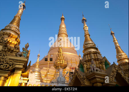 Detail der goldenen Turmspitzen beleuchtet durch die untergehende Sonne auf den klaren, blauen Himmel bei der Shwedagon Pagode in Yangon, Myanmar Stockfoto