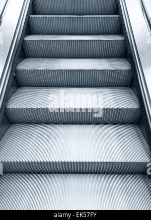 Glänzende Metall Rolltreppe hinauf bewegen, vertikale monochrome Foto mit blauen Tönung Filterwirkung Stockfoto