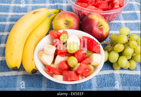 Ganze Bananen und Äpfel mit geschnittenen Wassermelone, Trauben und Bananen in Schale Stockfoto