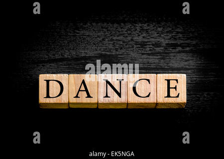 Wort Tanz. Hölzerne kleine Würfel mit Buchstaben auf schwarzem Hintergrund mit Kopie Speicherplatz isoliert. Konzept-Bild. Stockfoto