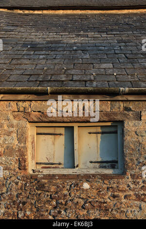 Alten verfallenden Fenster in Scheune mit Steinmauer und Schieferdach Stockfoto