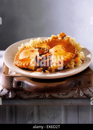 Gekochte Mahlzeit der traditionellen britischen Rindfleisch Steak in der ALE-Gebäck Kuchen & Kartoffelpüree serviert auf einem Teller in einem rustikalen Tabelle einstellen Stockfoto