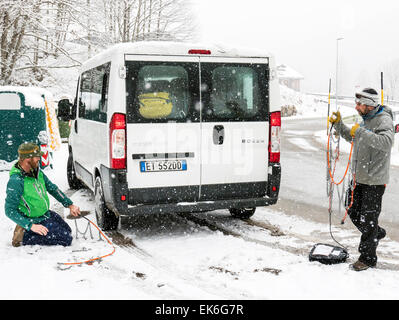 Amerikanische Skifahrer setzen Ketten für einen Mietwagen von van, Dolomiten, Norditalien Stockfoto