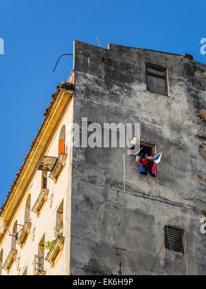 Die Wäsche trocknet in ein drittes Geschichtefenster eines alten Mehrfamilienhauses in Havanna Vieja, Kuba. Stockfoto