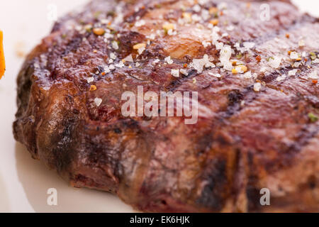 Lecker gegrilltes Rindersteak mit einem gezwirbelten Stück Butter und ein Zweig frischer Rosmarin garniert und serviert auf einem weißen Teller, enge u Stockfoto