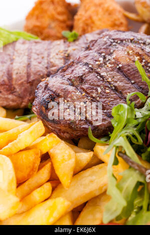 Gesunde Platte mit gemischtem Fleisch einschließlich gegrilltes Steak, knusprig Panierter Hühner- und Rindfleisch auf einem Bett aus frischen grünen grünen gemischten sa Stockfoto