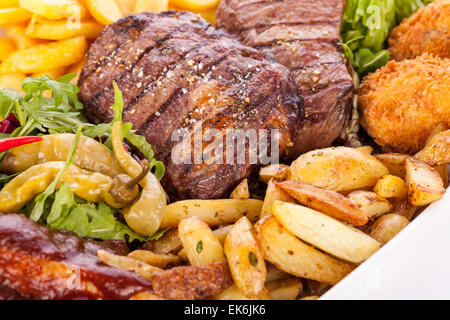 Gesunde Platte mit gemischtem Fleisch einschließlich gegrilltes Steak, knusprig Panierter Hühner- und Rindfleisch auf einem Bett aus frischen grünen grünen gemischten sa Stockfoto