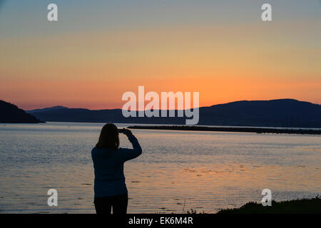 Lough Swilly, County Donegal, Irland. 7. April 2015. Irland Wetter: Eine Frau, die untergehende Sonne über Lough Swilly, markiert das Ende von einem warmen und sonnigen Frühlingstag in Donegal zu fotografieren.  Bildnachweis: George Sweeney/Alamy Live-Nachrichten Stockfoto