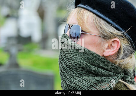 Eine maskierte Frau trägt ein Gelege vor den Mund, Sonnenbrille und eine schwarze Baskenmütze gehört ein Irish Republican Gedenken Stockfoto