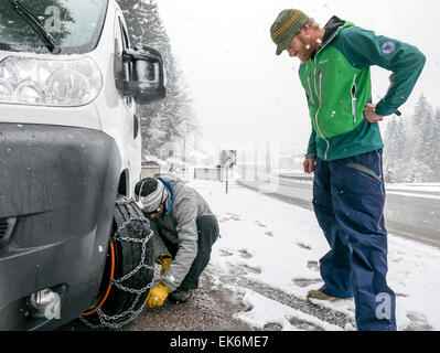 Amerikanische Skifahrer setzen Ketten für einen Mietwagen von van, Dolomiten, Norditalien Stockfoto