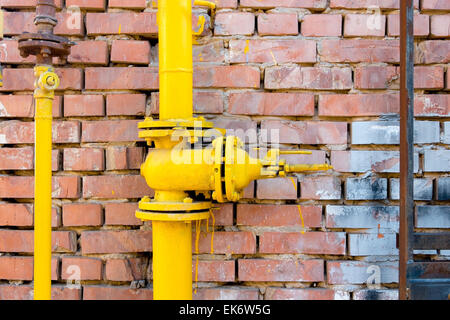 Gelbe Gasleitung und Ventil am roten Backsteinmauer, Exemplar Stockfoto