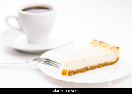 Stück frisch gebackenen Käsekuchen mit Tasse Kaffee auf weißen Tisch espesso Stockfoto