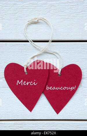 Vertikales Bild beschriften Sie zwei rote Herzen mit weißen Band auf weißem Holz Hintergrund Beaucoupe mittels französischen Text Merci danke Yo Stockfoto