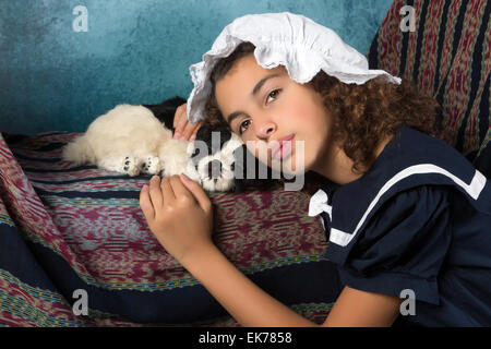 Süßes viktorianisches Mädchen posiert im alten Stil mit ihrem Hund Stockfoto