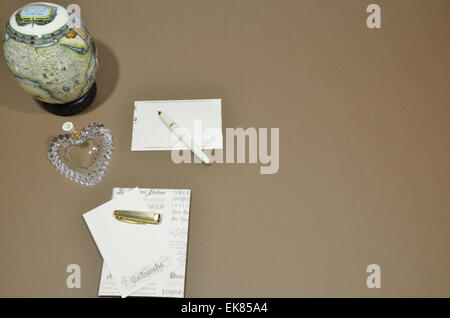 Satz von Buchstaben, Stift Halter in Herzform, Stift und kleine Weltkugel auf braunem Hintergrund. Stockfoto