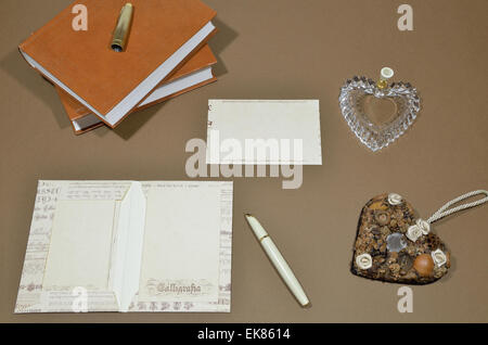 Satz von Buchstaben, Stift, Stifthalter in Herzform, Herz und Bücher auf braunem Hintergrund. Stockfoto