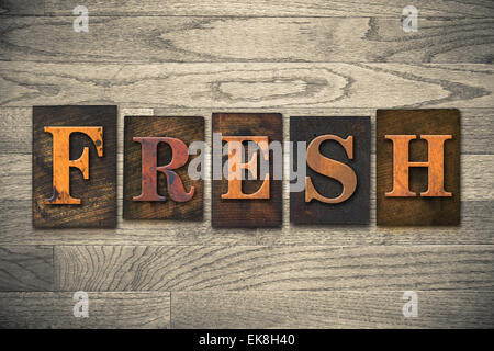 Das Wort "Frisch" Thema in Vintage, Tinte befleckt, hölzerne Buchdruck Typ auf gemasertem Holz Hintergrund geschrieben. Stockfoto