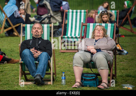 London, UK. 8. April 2015. In der Sonne dösen. Die Frühlingssonne bringt Arbeitnehmer und Touristen um die Mittagszeit. Sie genießen in den Liegestühlen entspannen oder auch die Verwendung als Outdoor-Büros. Green Park, London, 8. April 2015. Bildnachweis: Guy Bell/Alamy Live-Nachrichten Stockfoto