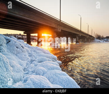 Verschneite Brücke und frostigen Sonnenuntergang am Fluss im Winter in der Ukraine Stockfoto