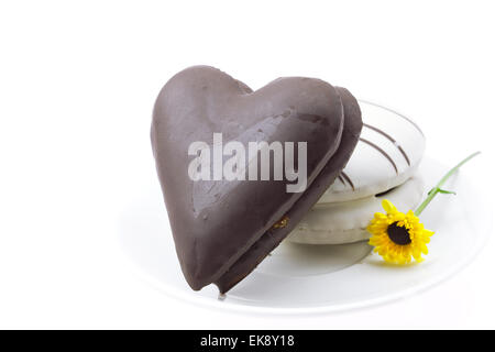 Kuchen in der Form Herz und Blume auf einem Teller isoliert auf weiss Stockfoto