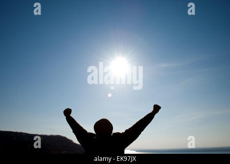 Mann mit seinen Armen gegen den blauen Himmel auseinander Stockfoto