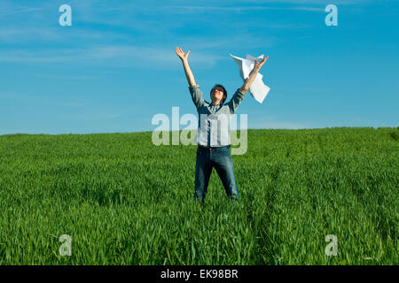 junger Mann werfen eine Papier auf der grünen Wiese Stockfoto