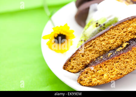 Kuchen in der Form des Herzens und eine Blume auf dem grünen Tuch liegend Stockfoto