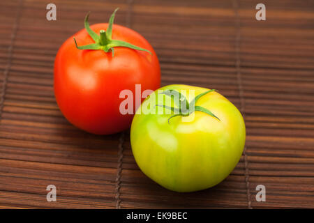 grüne und rote Tomaten auf einer Bambusmatte Stockfoto