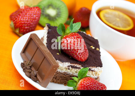 Tee mit Zitrone, Schokolade, Kiwi, Kuchen und Erdbeeren auf der Ora liegend Stockfoto