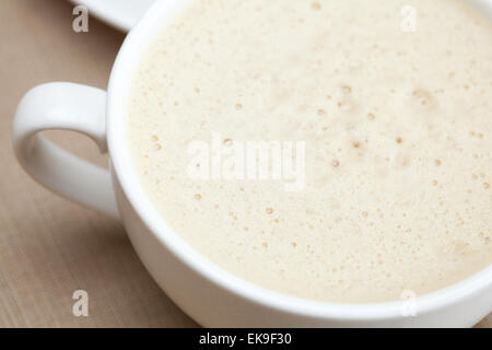 Tasse Cappuccino, ein Stück Kuchen mit Nüssen auf dem Teller liegen Stockfoto