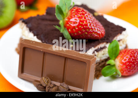 Tee mit Zitrone, Schokolade, Kiwi, Kuchen und Erdbeeren auf der Ora liegend Stockfoto