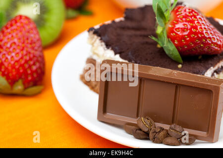 Tee mit Zitrone, Schokolade, Kiwi, Kuchen und Erdbeeren auf der Ora liegend Stockfoto