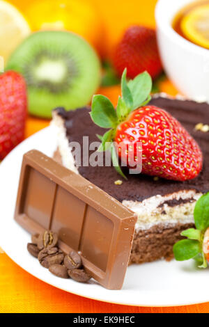 Tee mit Zitrone, Schokolade, Kiwi, Kuchen und Erdbeeren auf der Ora liegend Stockfoto